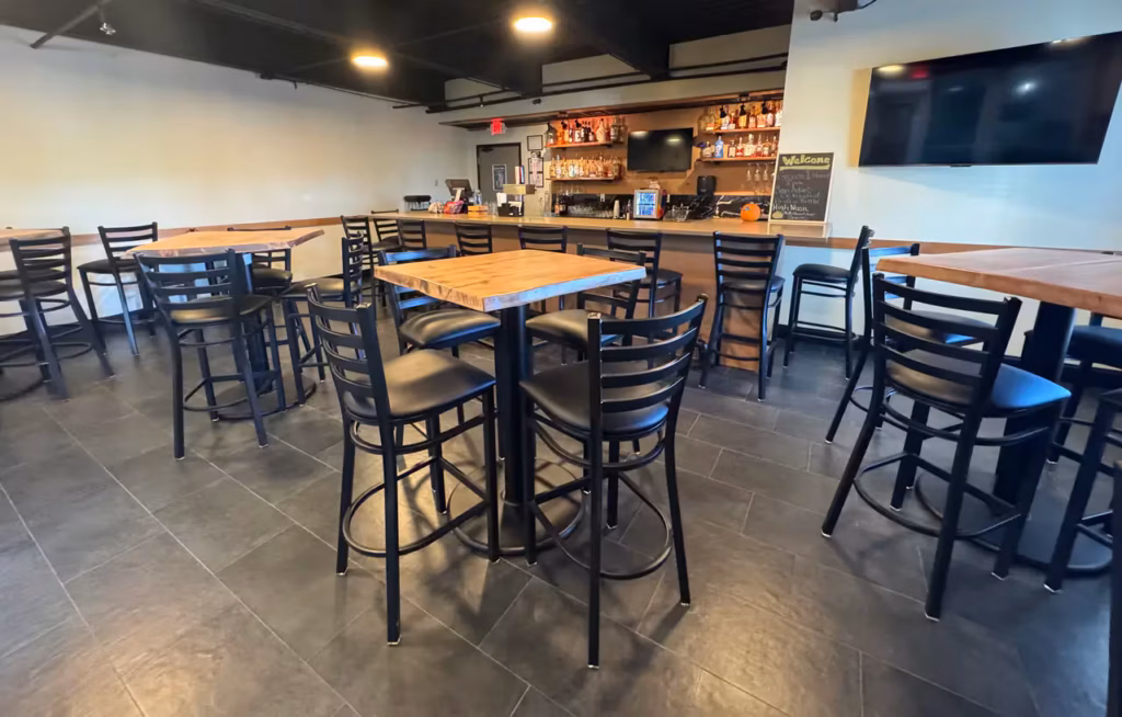 Hotels with indoor pool Battle Creek breakfast area featuring a modern dining space with wooden tables, high chairs, and a cozy bar-style setup for guests.